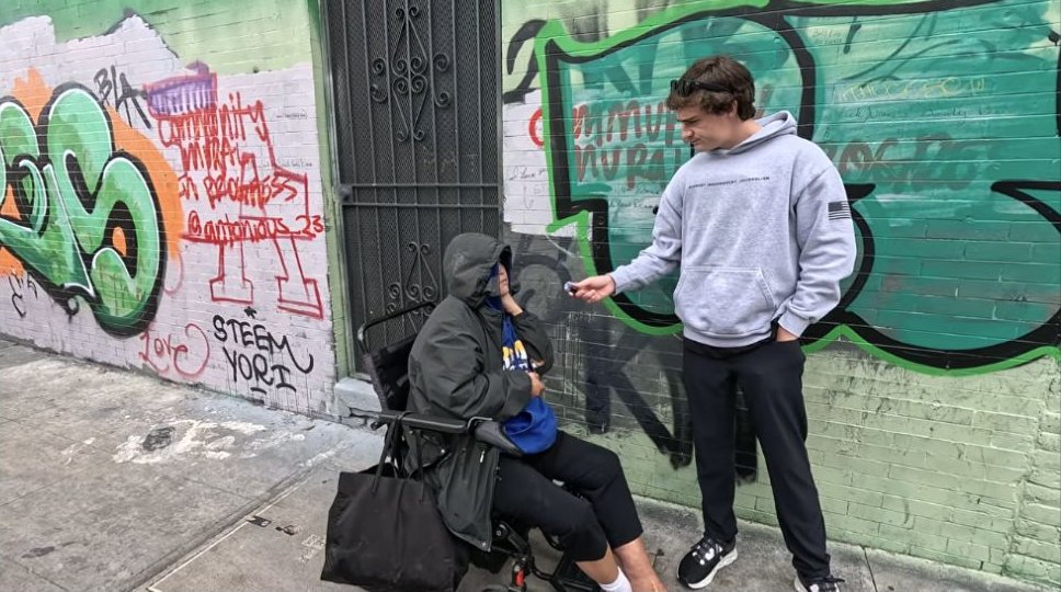 Nick Shirley holds a microphone during a street interview on Skid Row.